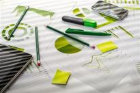 Image of an office desk with financial documents, charts and digital gadgets